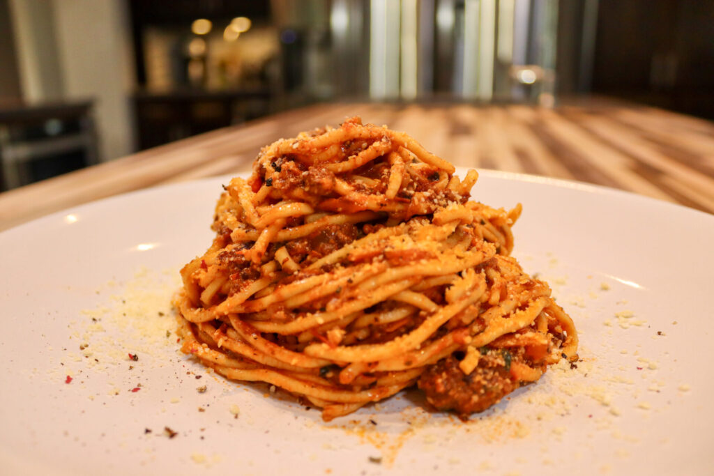 Spaghetti Bolognese in detail from side, kitchen in background