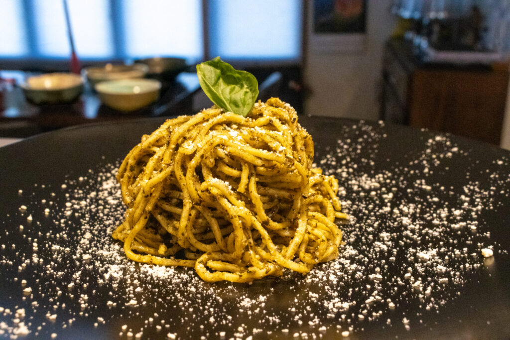 Pesto Spaghetti on the black plate, side medium distance view with dining room at the background