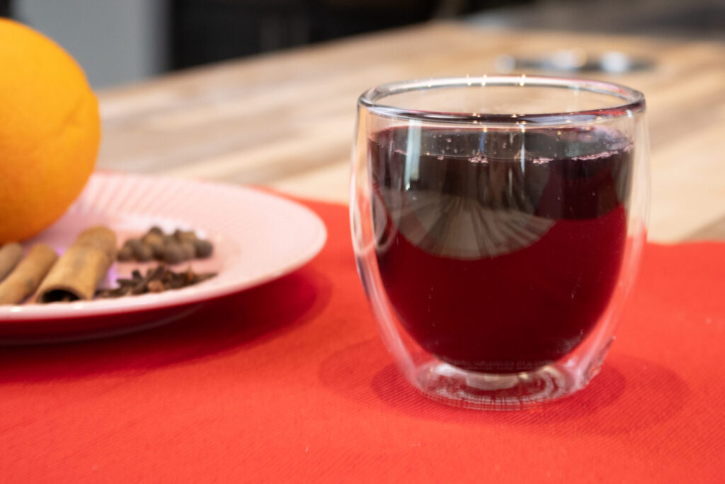 Czech Mulled Wine - Svarak is on the countertop with red table settings and orange and spices in the background.