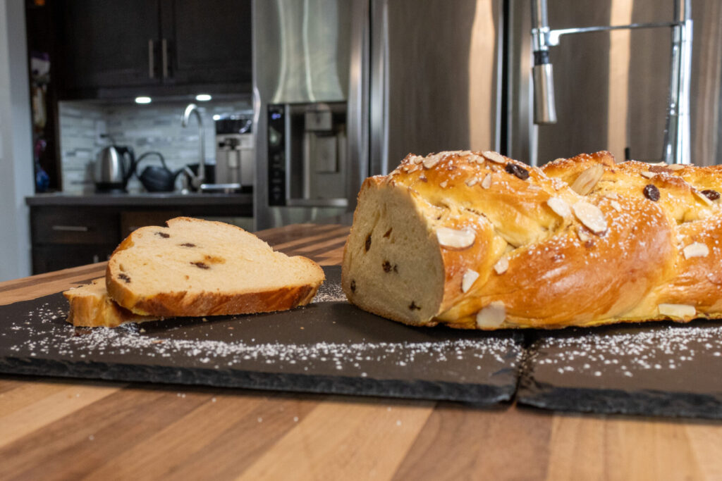 Sweet Czech Christmas Bread Vanocka Houska - side shot from distance showing a slice and rest of the loaf, kitchen in the background