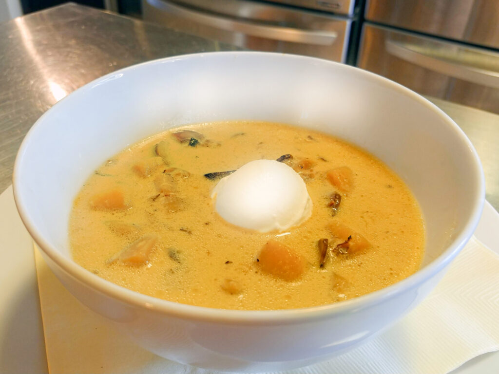 Czech Potato Soup Bramboračka in white soup bowl side shot with refriegerator in the background