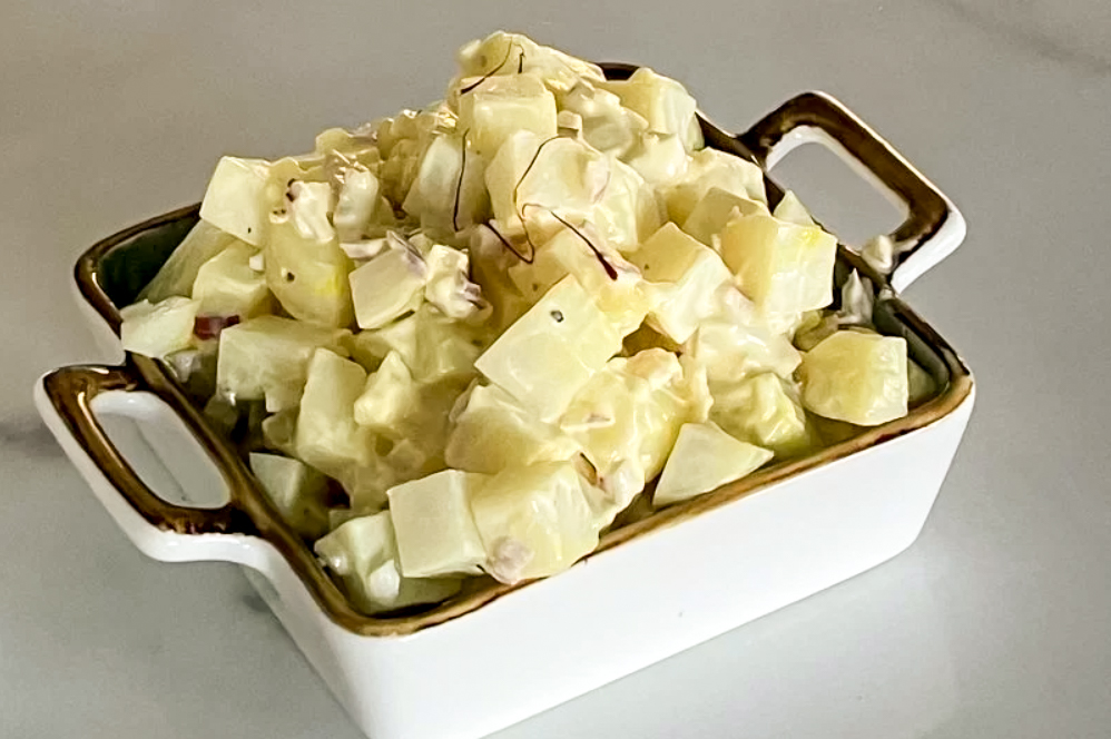 Saffron Mayo Potato Salad on the tray on the white surface, side shot