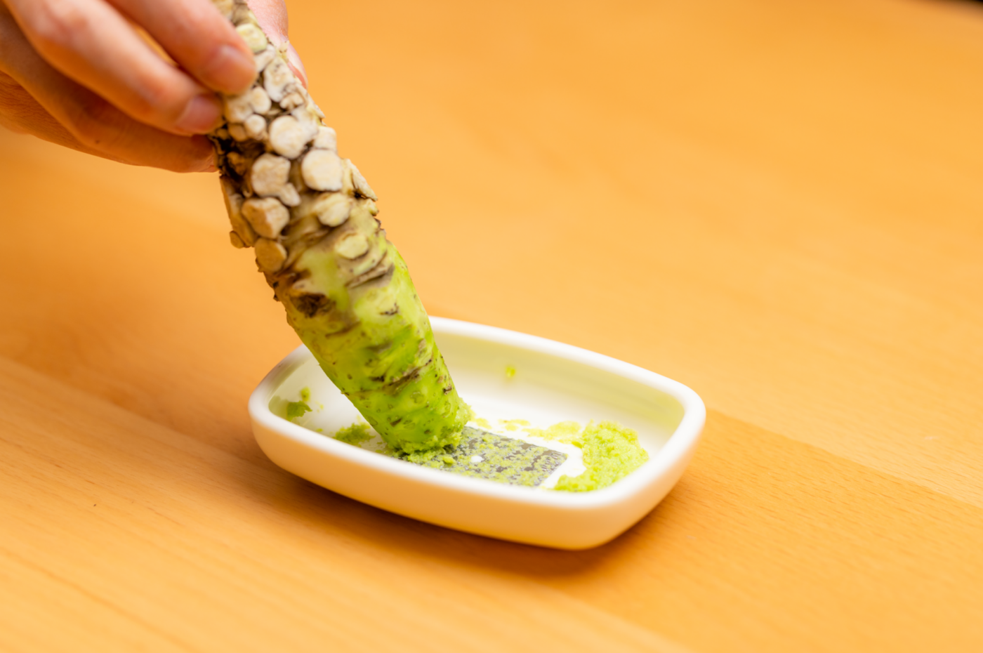 wasabi root being grated on grater for wasabi paste or sauce