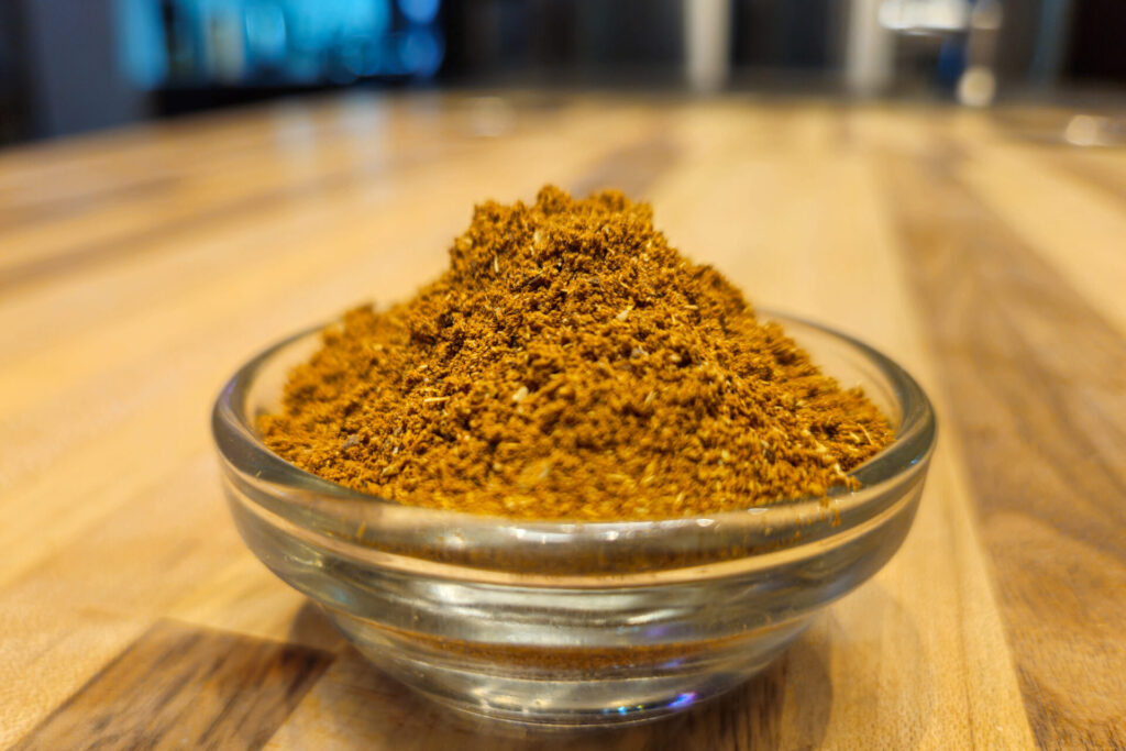 Garam Masala Seasoning Recipe in the small mixing bowl, side detail shot with kitchen in the background